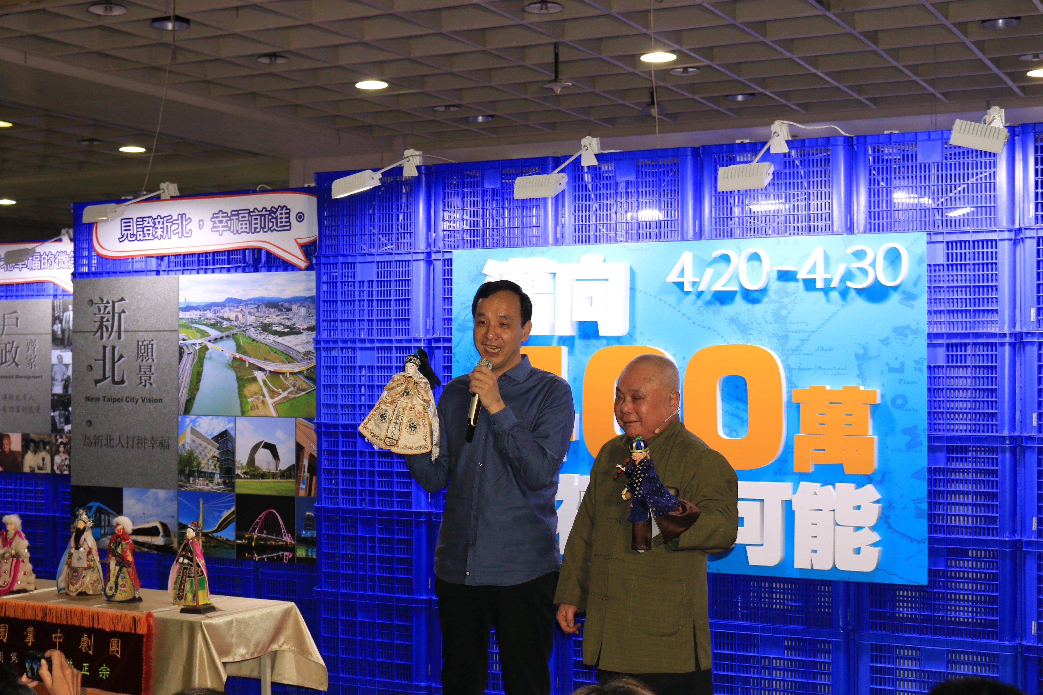 「新北戶政展」，今（20）日在板橋火車站B1展出，由新莊在地百年歷史的小西園布袋戲第三代-新西園布袋戲偶（右穿綠衣者）與朱立倫市長（左穿藍衣服者）互動熱鬧揭幕