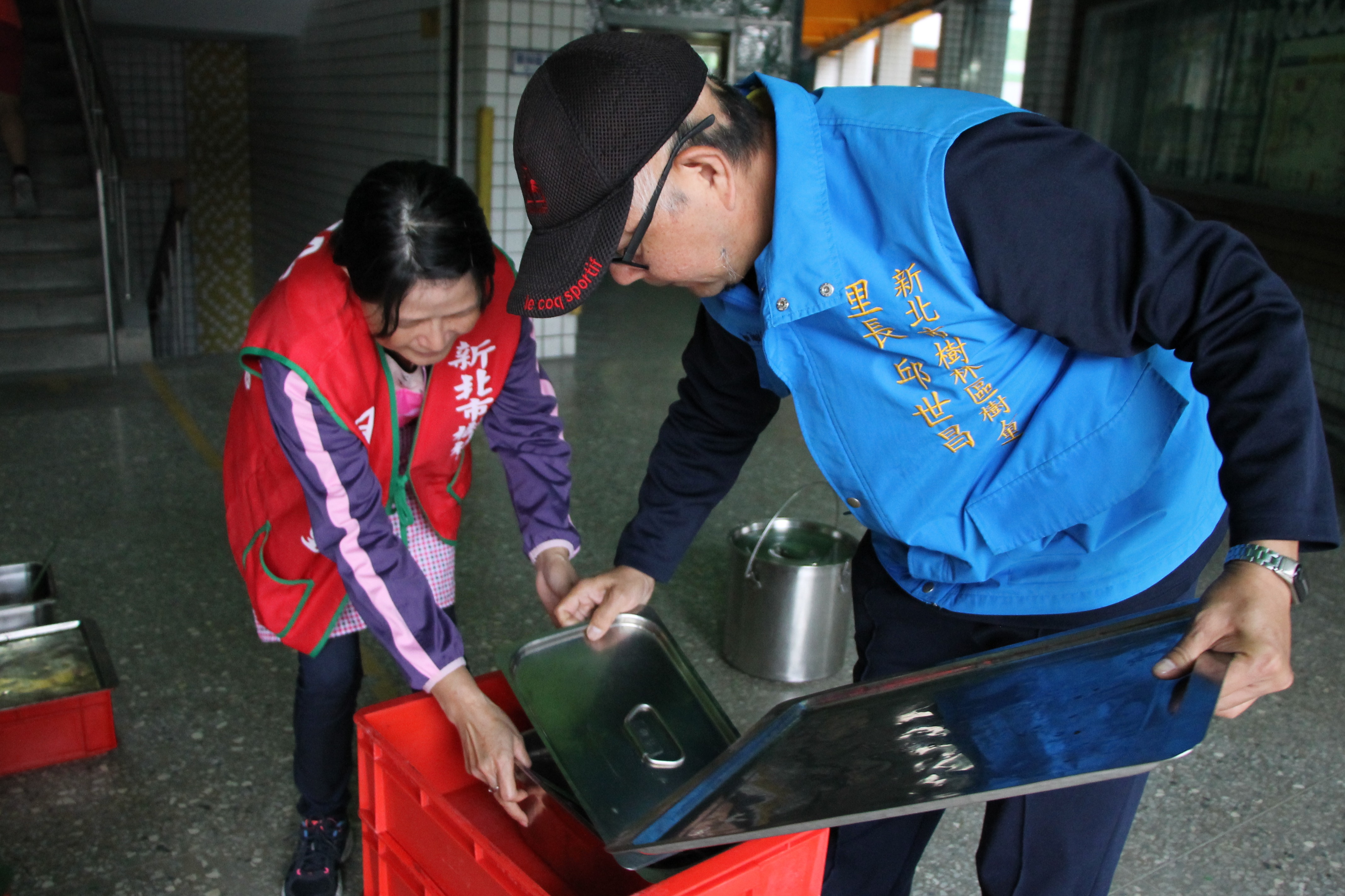 樹人里長邱世昌（右藍外套者）和志工們將學生們吃不完的剩菜分裝成愛心餐盒。