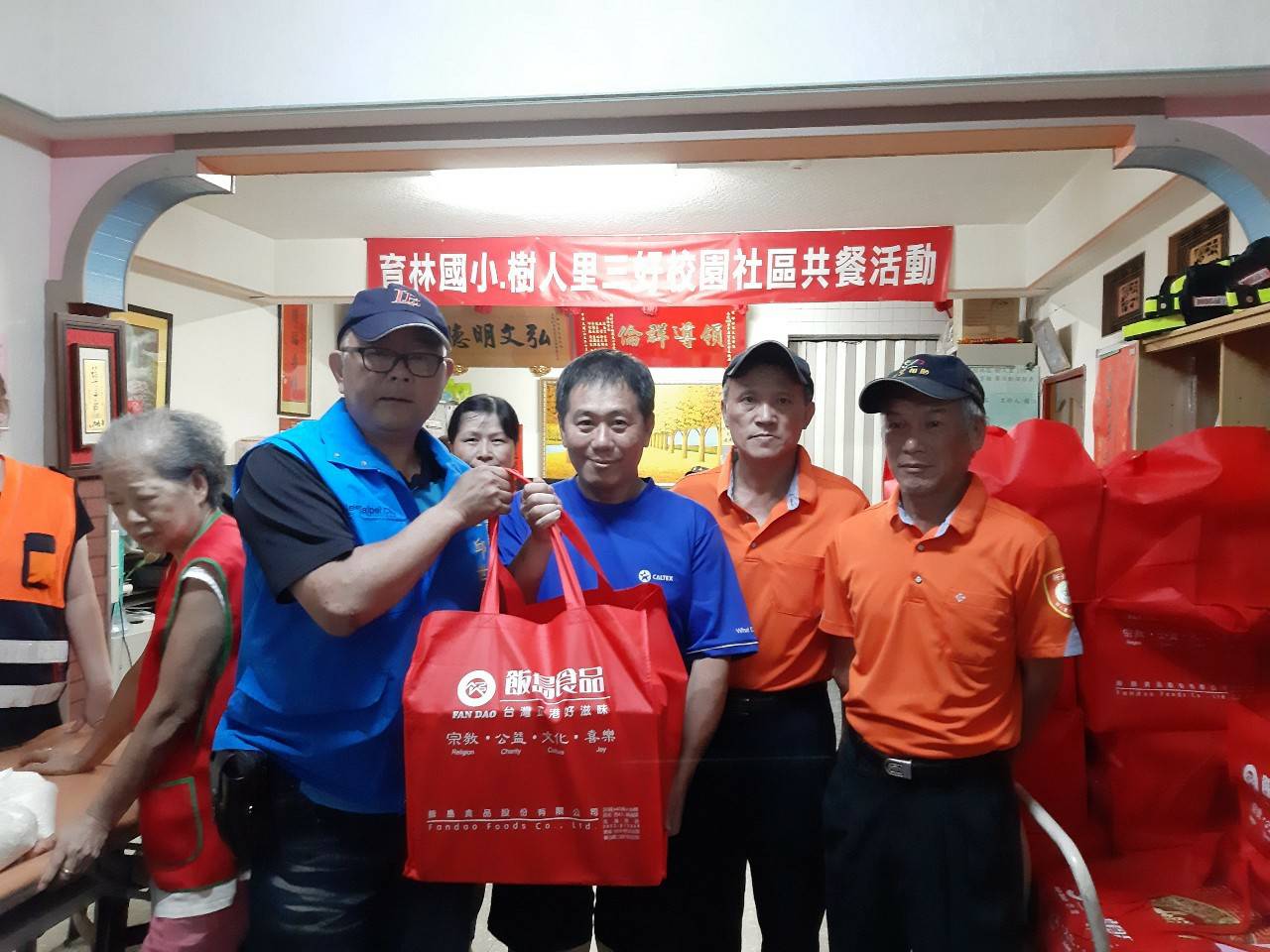 里長邱世昌（左藍背心者）和志工們將愛心餐盒分送給里內長者及獨居老人，減少食物浪費。